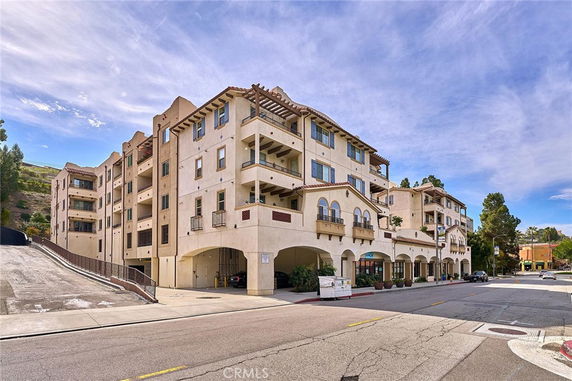 Front view of a multi-story residential building with arched entrances and balconies.