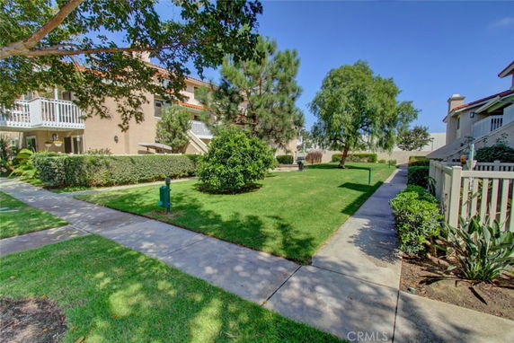 View of residential buildings with green lawn and pathways.