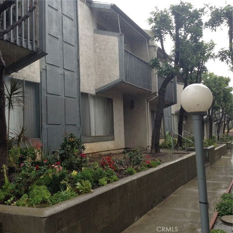 Front view of a multi-story building with balconies and a garden area.