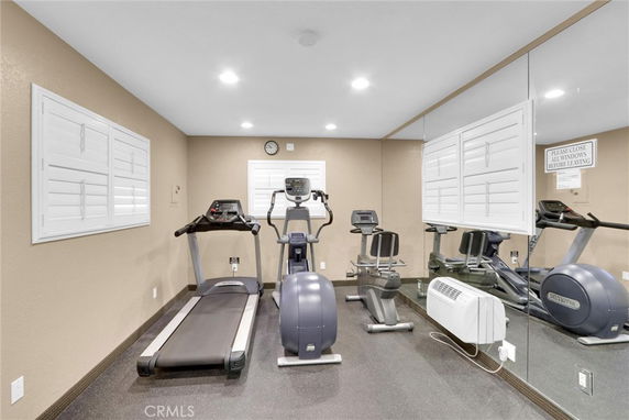 Room with exercise equipment including treadmill and stationary bikes.
