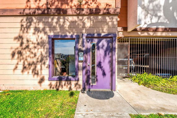 Front view of a building entrance with a purple door and adjacent window.