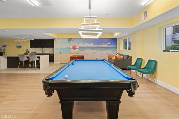 Indoor recreation area with a pool table, seating, and kitchenette.