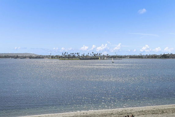 Wide-angle view of a body of water with distant palm trees and boats.