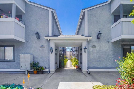 Front view of a multi-story residential building with balconies and a central gated entrance.
