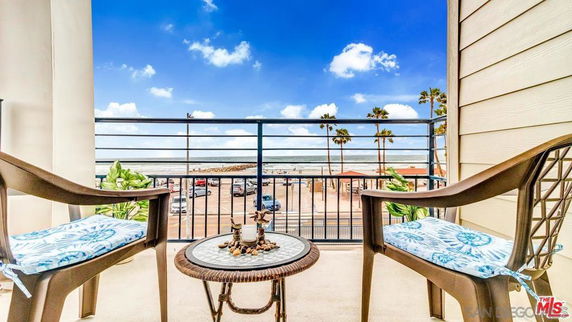 Outdoor patio with two chairs overlooking a beach and ocean view.