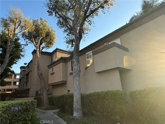 Front view of a multi-story residential building with beige exterior and small balconies.