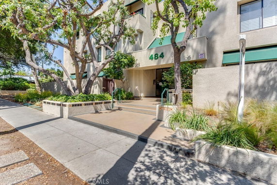 Front view of a multi-story building with trees and a pathway leading to the entrance.