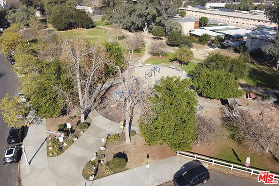 Aerial view of an outdoor play area with playground equipment surrounded by trees.