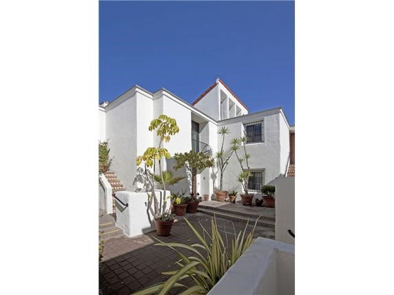 Front view of a modern house with white walls and a courtyard with potted plants.