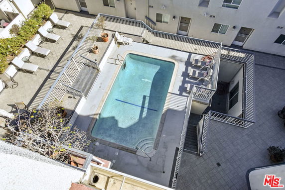Aerial view of a swimming pool area with surrounding lounge chairs and potted plants.