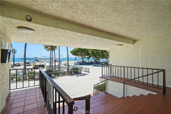Covered outdoor area with railings and a view of the ocean and pier.