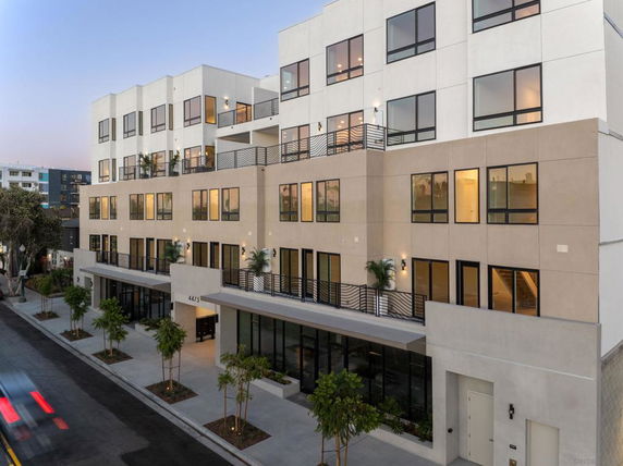 Front view of a modern multi-story building with numerous windows and balconies.