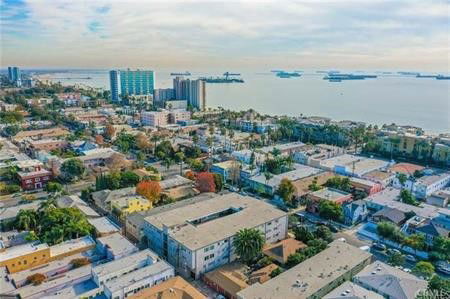 Aerial view of a coastal urban area with multiple buildings and distant ships on the water.