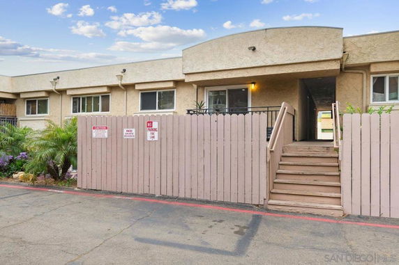 Front view of a building with stucco facade and wooden fence.