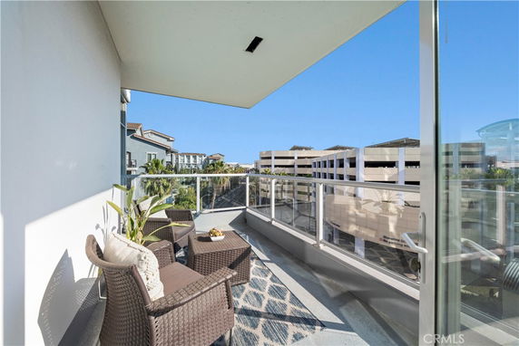 Outdoor balcony area with furniture, glass railing, and view of surrounding buildings.