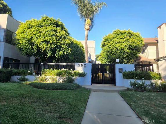 Front view of a building with a gated entrance and manicured landscaping.