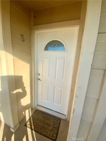 Front view of a house entrance with a white door and welcome mat.