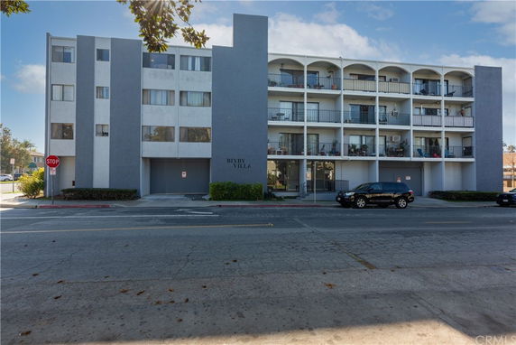 Front view of a multi-story building with balconies and a sign saying Bixby Villa.