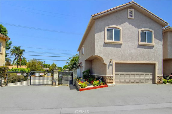 Front view of a two-story house with a garage and gated entrance.