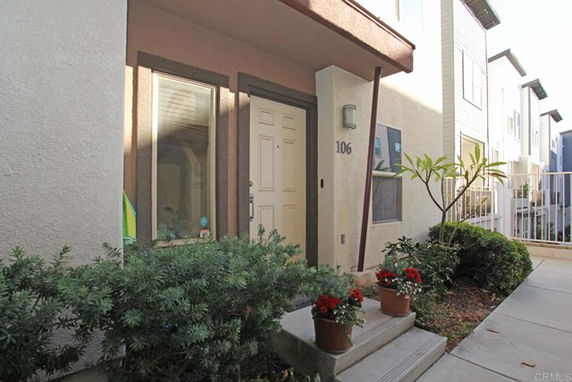 Front view of a house with a small entrance pathway and potted plants.