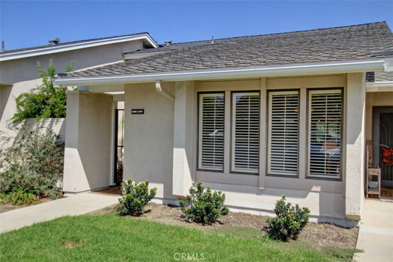 Front view of a single-story house with a covered entrance and large windows with shutters.