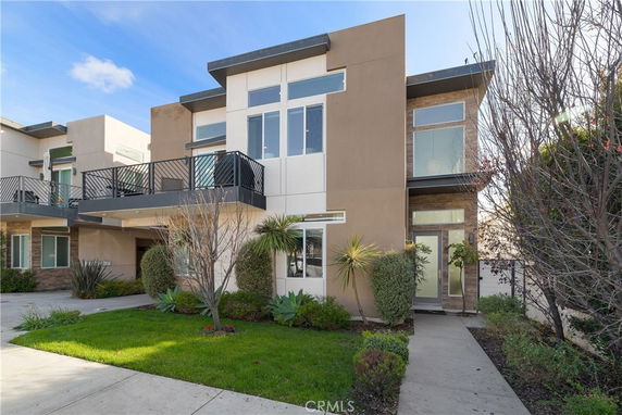 Front view of a modern two-story house with a balcony and large windows.