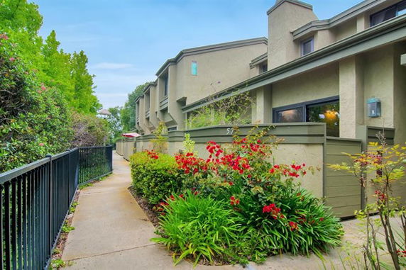 Front view of a multi-story townhouse with a pathway and garden.
