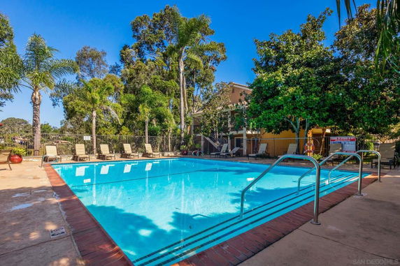 Outdoor swimming pool area with lounge chairs and surrounding trees.