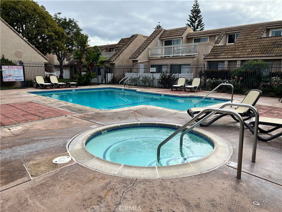 Outdoor swimming pool area with adjacent jacuzzi and lounge chairs.
