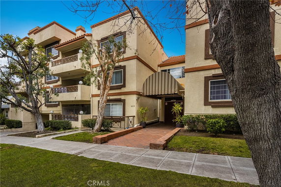 Front view of a multi-story residential building with balconies and an entrance canopy.