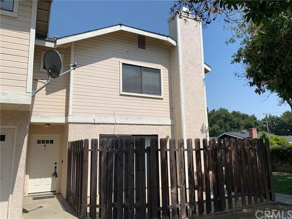 Front view of a two-story house with a fenced entrance and a chimney.