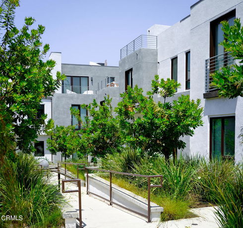 Front view of a multi-story building with balconies and greenery.