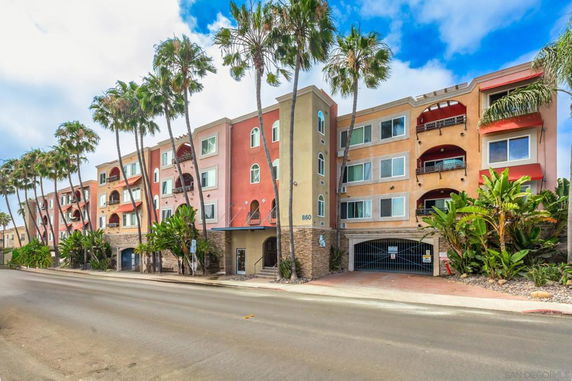Front view of a multi-story residential building with a gated parking area.