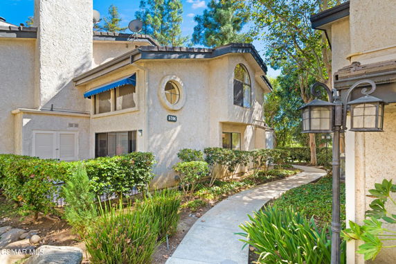 Front view of a multi-story house with a pathway and surrounded by greenery.