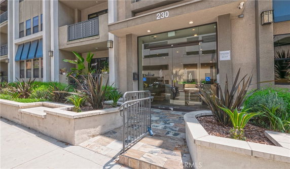 Front view of a building entrance with glass doors and balconies above.