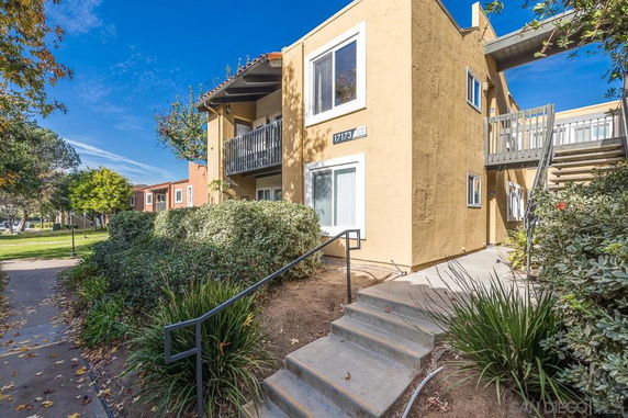 Front view of a two-story apartment building with exterior stairs and a small balcony.