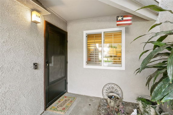 Front view of a house entrance with a black screen door and a window with shutters next to it.