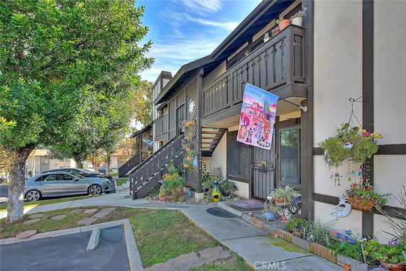 Front view of a two-story residential building with a flag and stairs leading to an upper balcony.