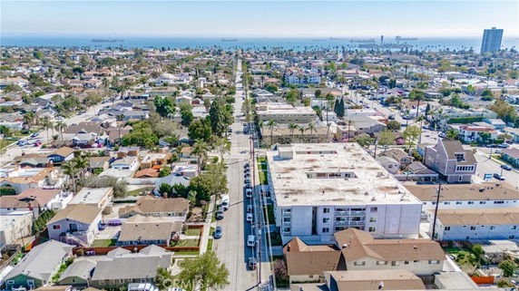 Aerial view of a residential neighborhood with houses and streets extending towards the ocean in the background.