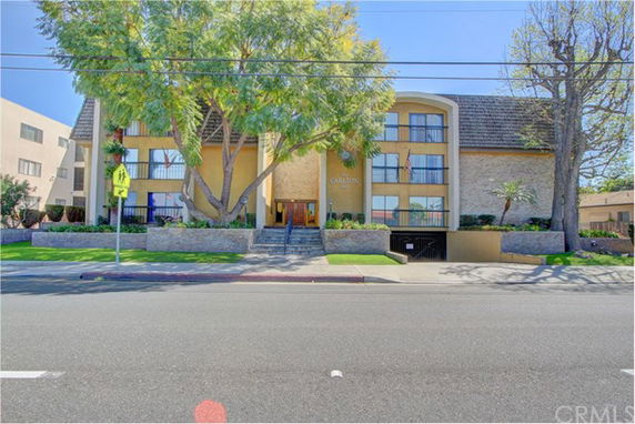 Front view of a multi-story building with large windows and a pitched roof.
