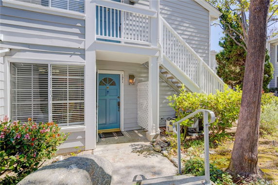 Front view of a multi-level house with an external staircase and blue door.