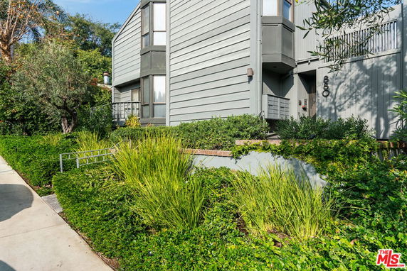 Front view of a modern two-story house with grey siding and landscaped greenery.