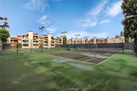 View of a tennis court with buildings in the background.