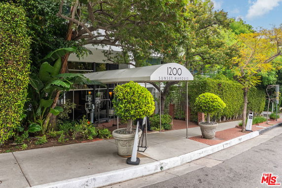 Front view of a building with entrance canopy and street-side greenery.