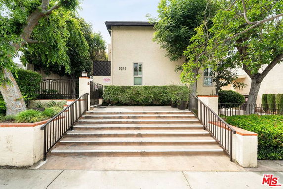 Front view of a beige two-story building with a staircase leading up to the entrance.