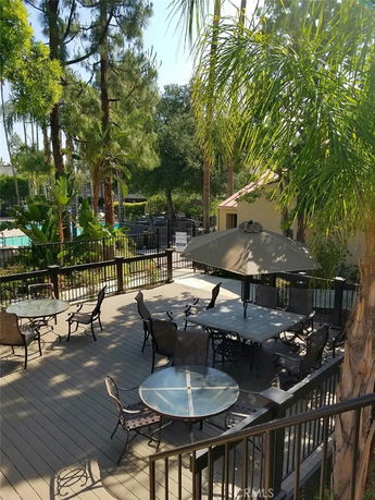Outdoor seating area with tables and chairs under umbrellas, surrounded by trees.