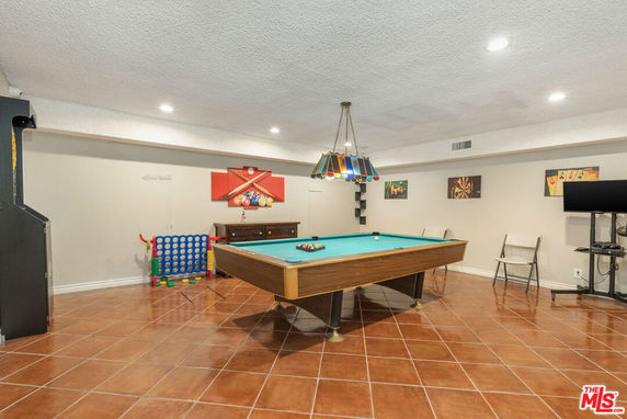 Recreation room with a pool table and arcade machine.