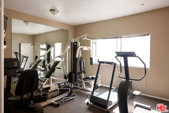 Small indoor gym with exercise equipment and a large mirror.