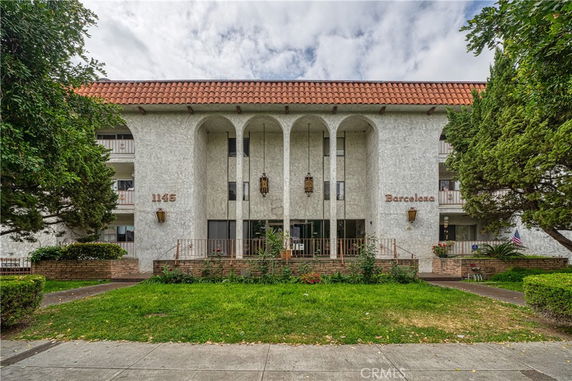 Front view of a multi-story building with a tiled roof and arches.