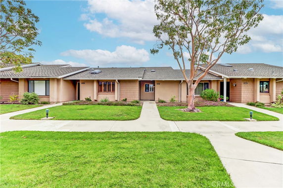 Front view of a single-story house with multiple entrance doors and a well-maintained lawn.